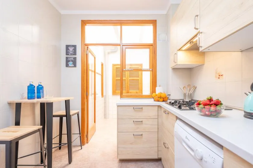 A bright kitchen with light cabinets, a countertop, and a window.