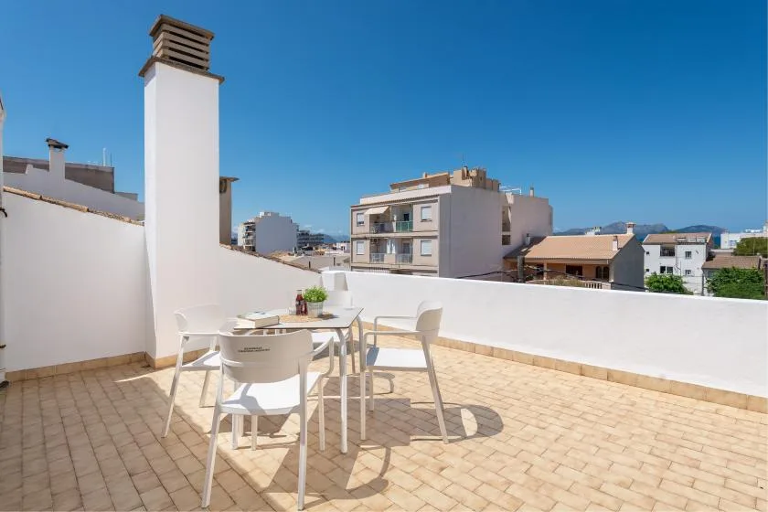 A sunny rooftop terrace with outdoor seating and views of nearby buildings.