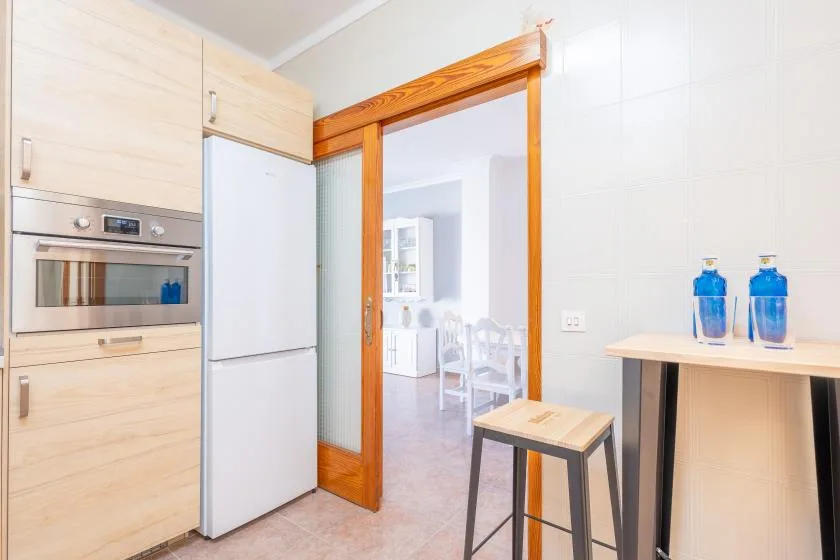 A bright kitchen with light wood cabinets and a wooden-framed doorway.