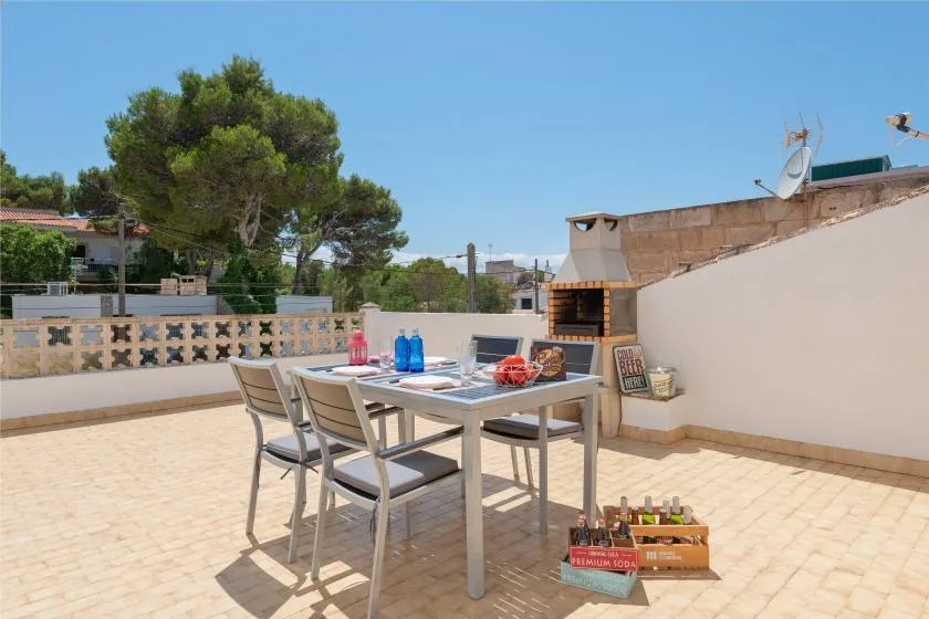 A sunny rooftop terrace with an outdoor dining table and built-in grill.