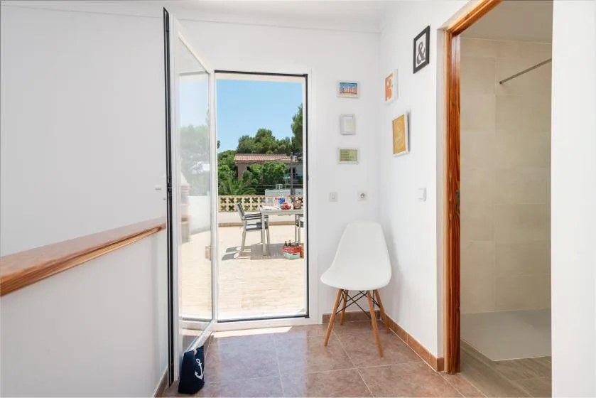 A bright room opens onto a patio, with a chair beside the doorway.