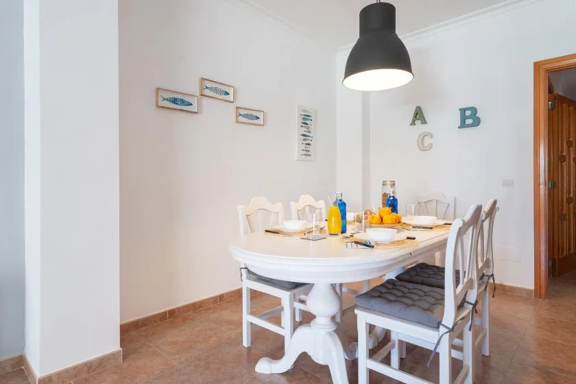 A dining room with a table set beneath a black pendant light.