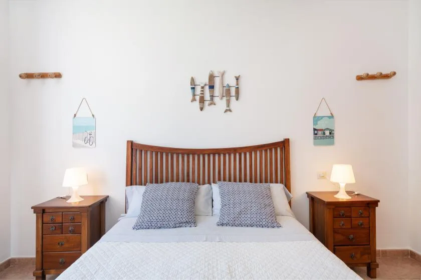 A bedroom with a bed between two wooden bedside tables.