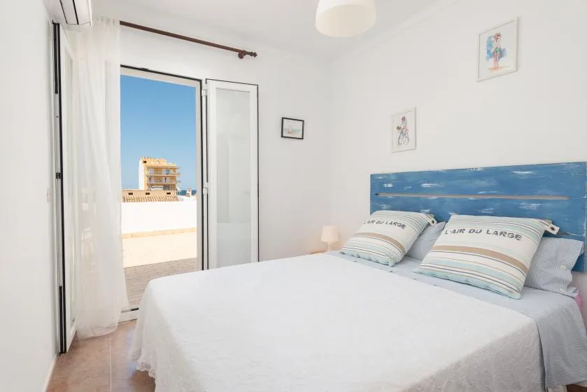 A bright bedroom with a double bed and an open balcony door.
