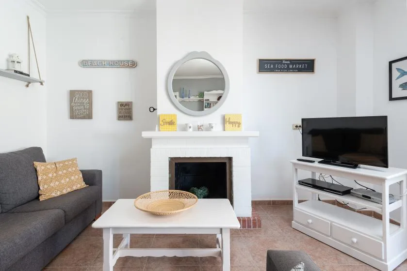A bright living room with a fireplace, seating, and a television.