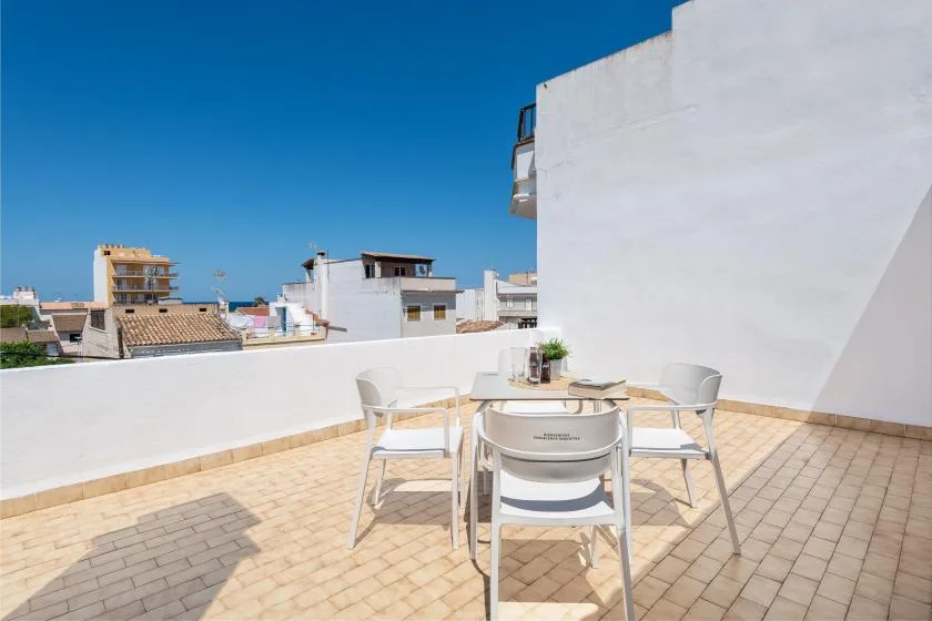 A rooftop terrace with a table and seating overlooking nearby buildings.