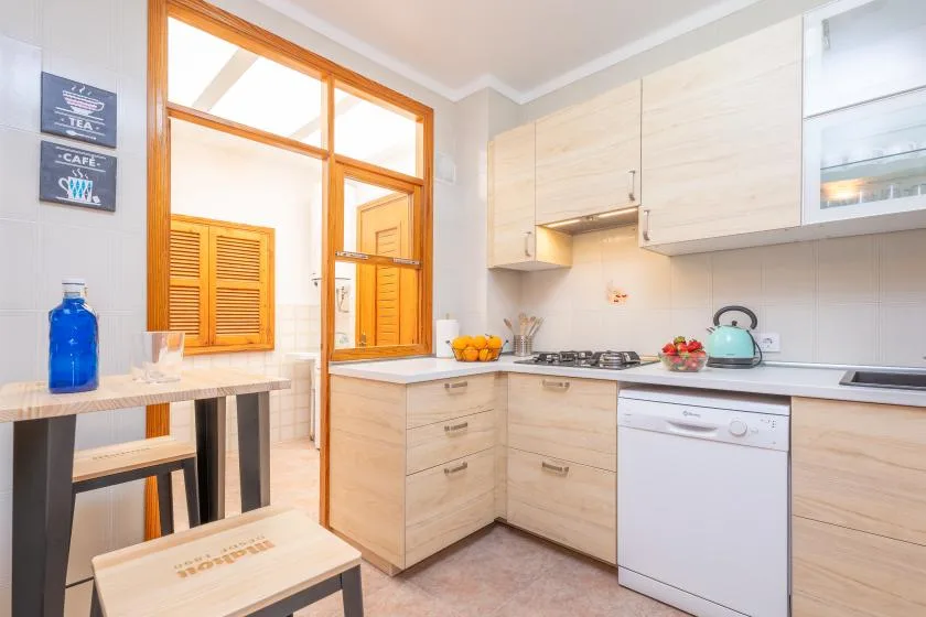 A bright kitchen with pale cabinets, a countertop, and a window.