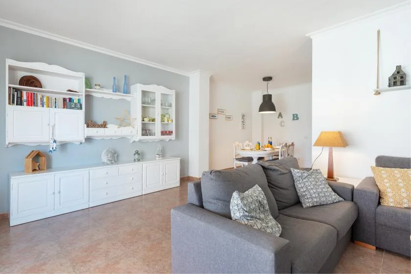 A living room with gray seating beside white built-in cabinets and a dining area.