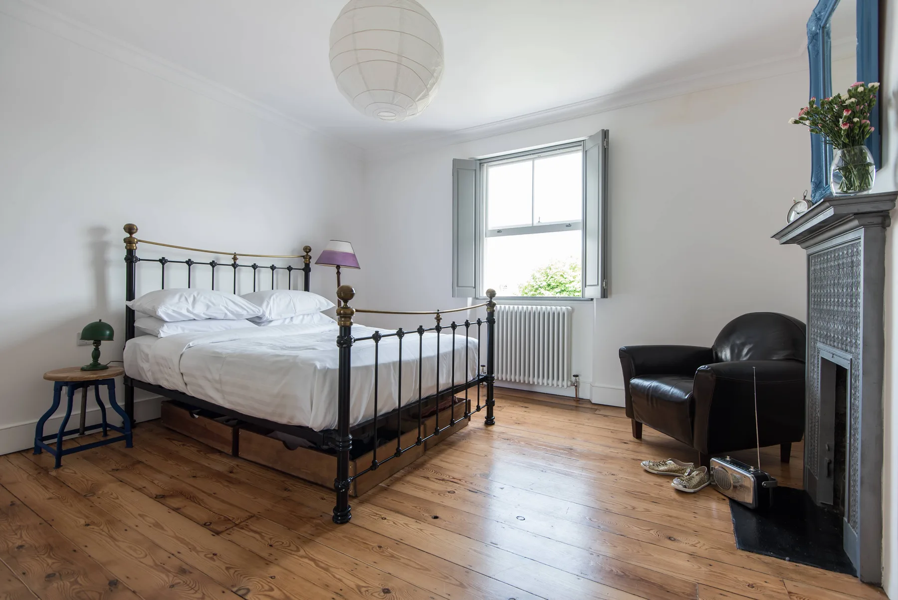 A bedroom with a black metal bed, a window, and a sitting area.