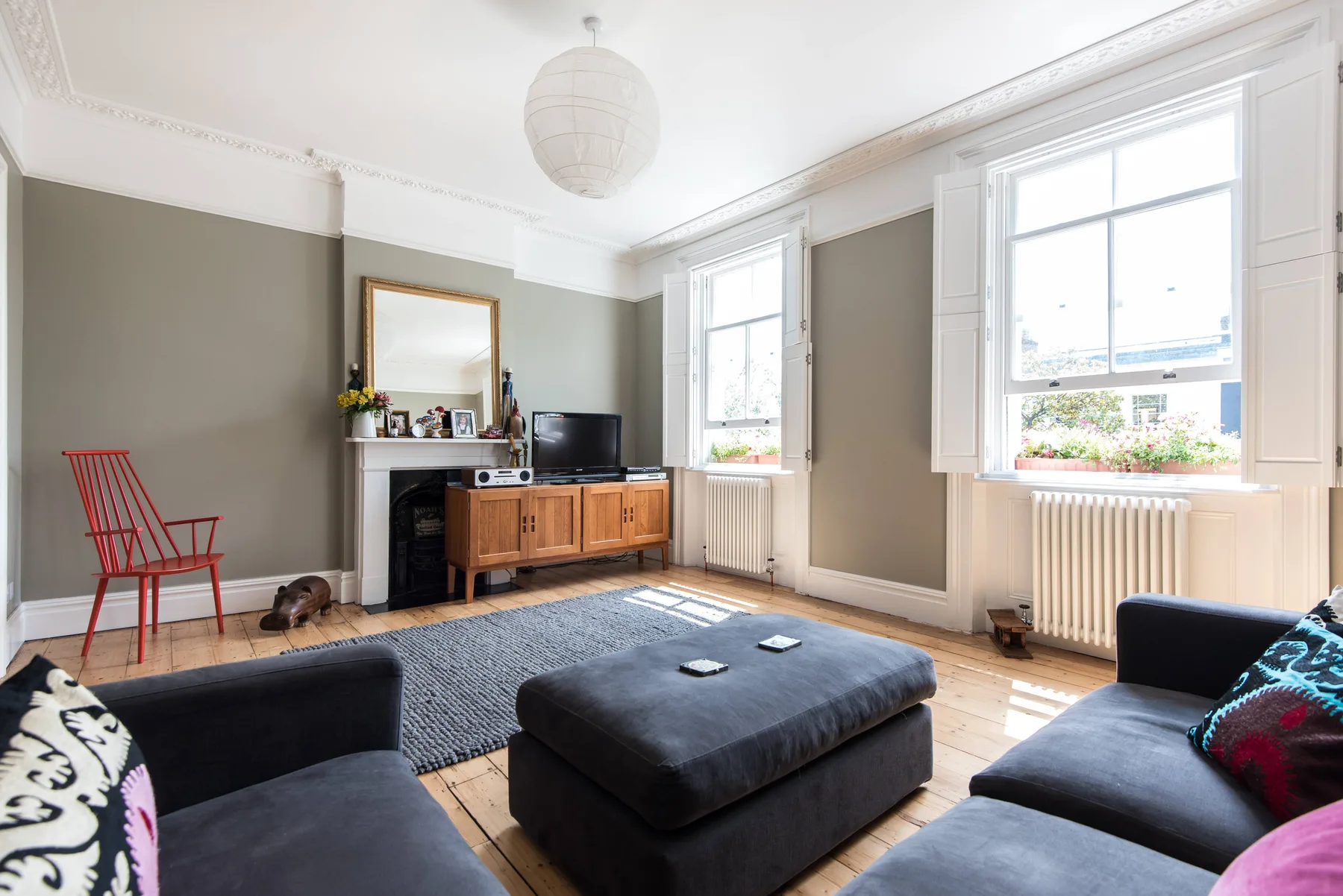 A bright living room with dark seating and large windows.