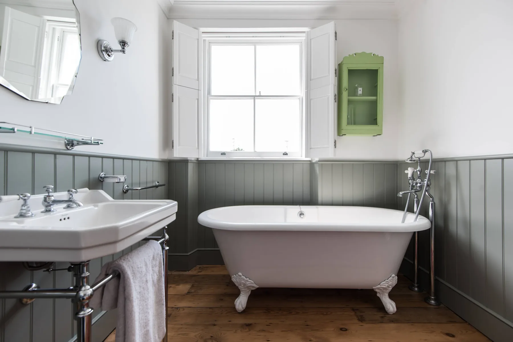 A bright bathroom with a freestanding bathtub beneath a window.
