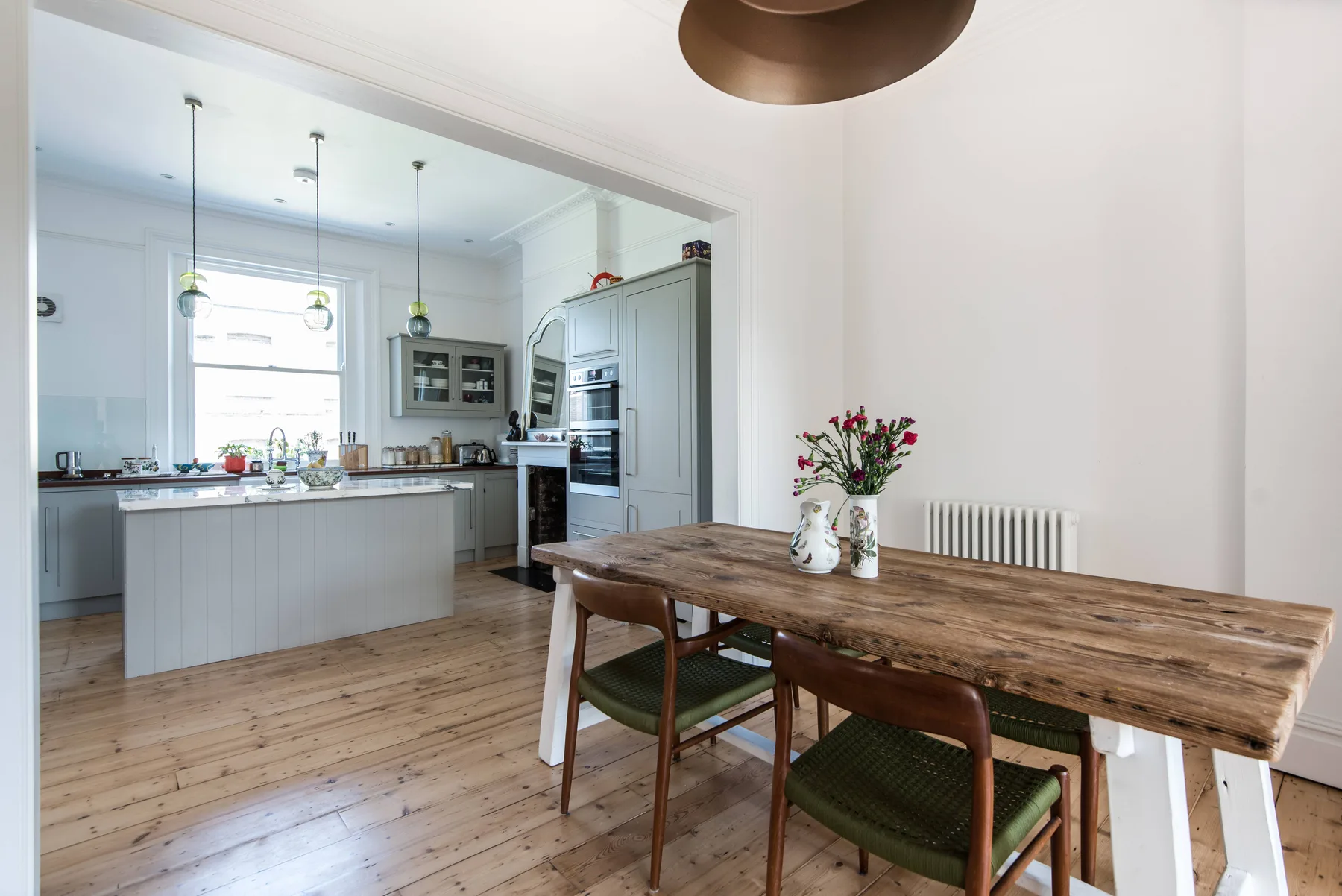 A dining area with a wooden table and chairs beside an open kitchen.