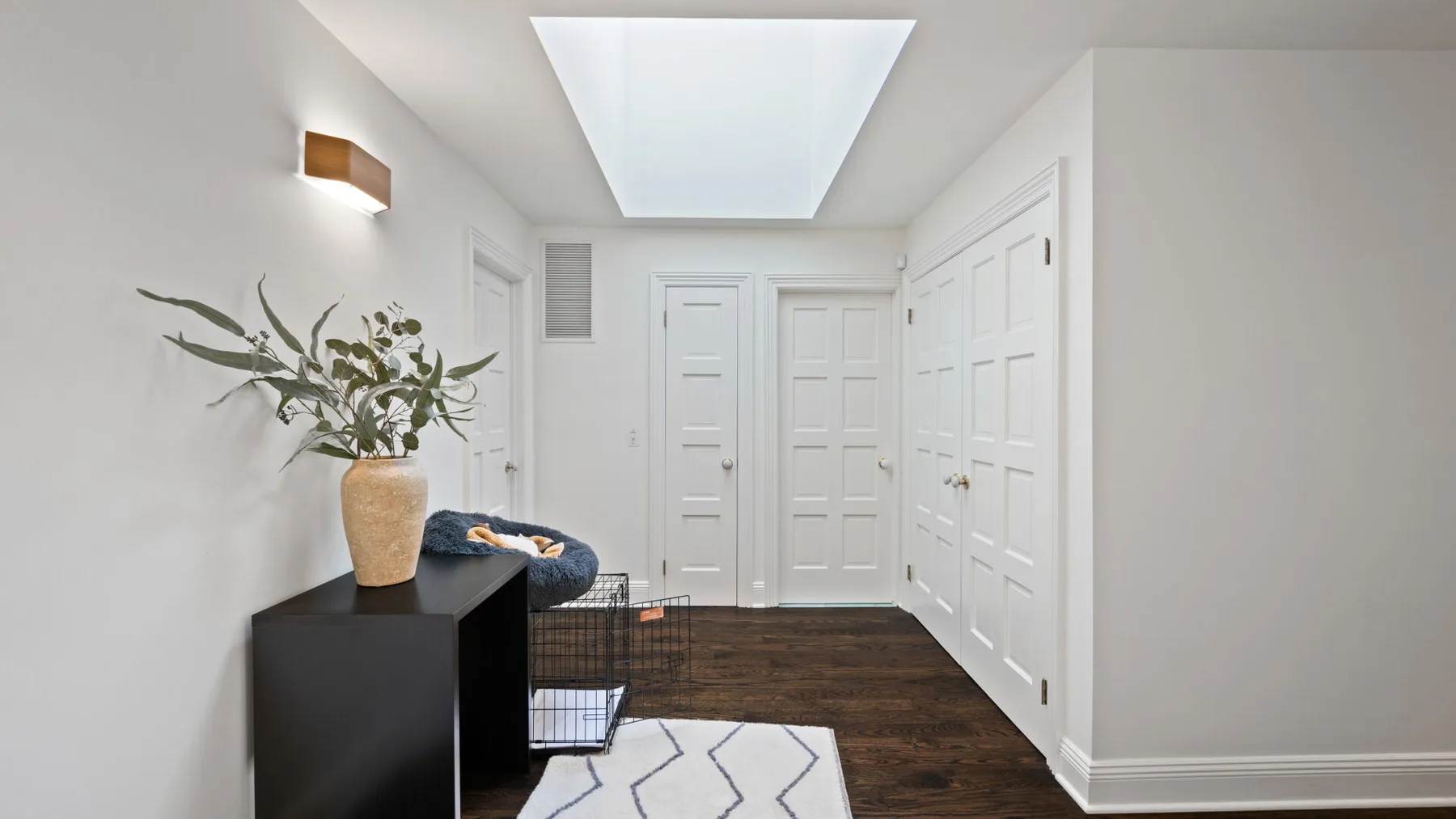 A bright white hallway with paneled doors and a dark wood floor.