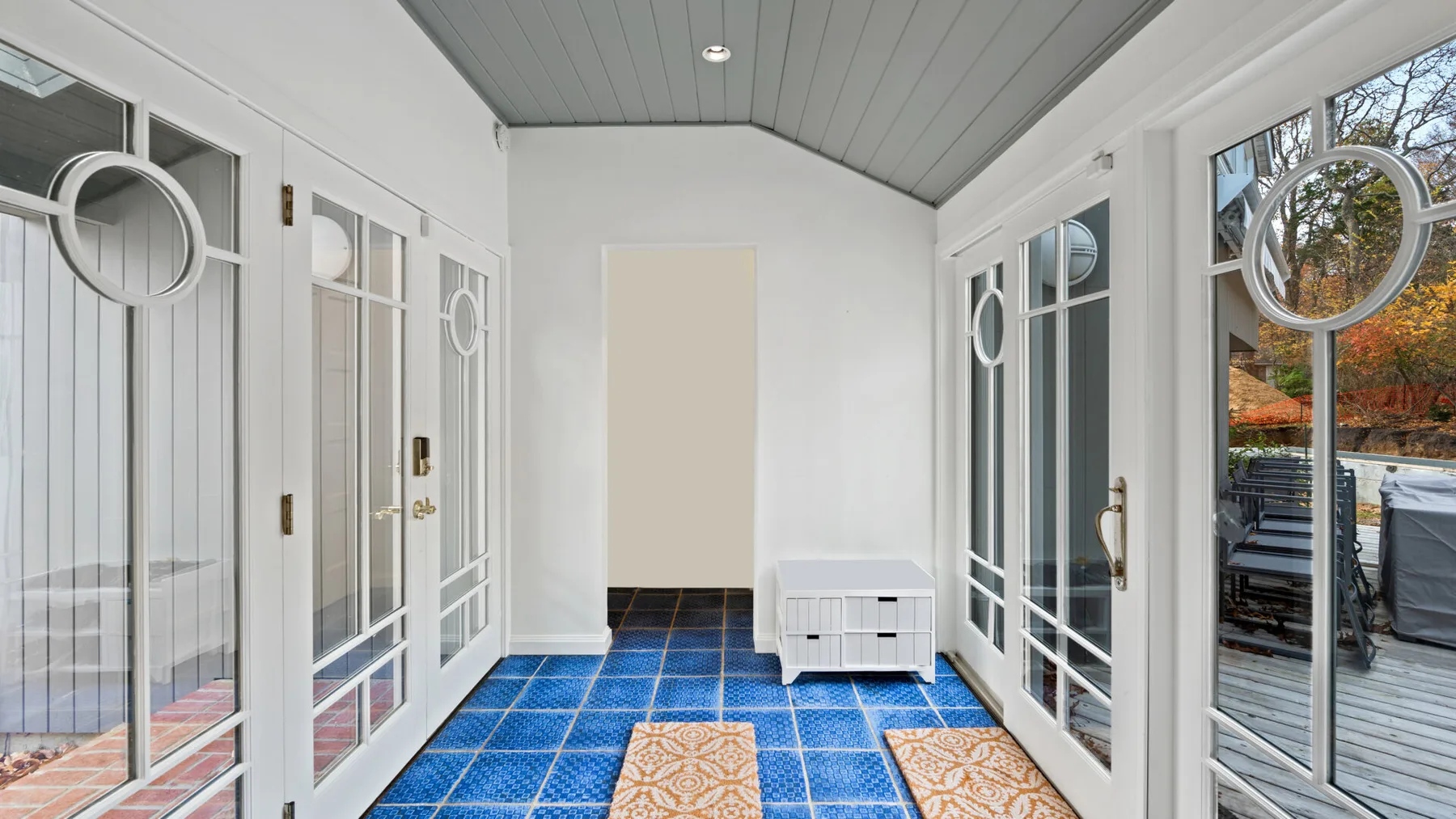 A bright enclosed porch with large windows and blue tiled flooring.