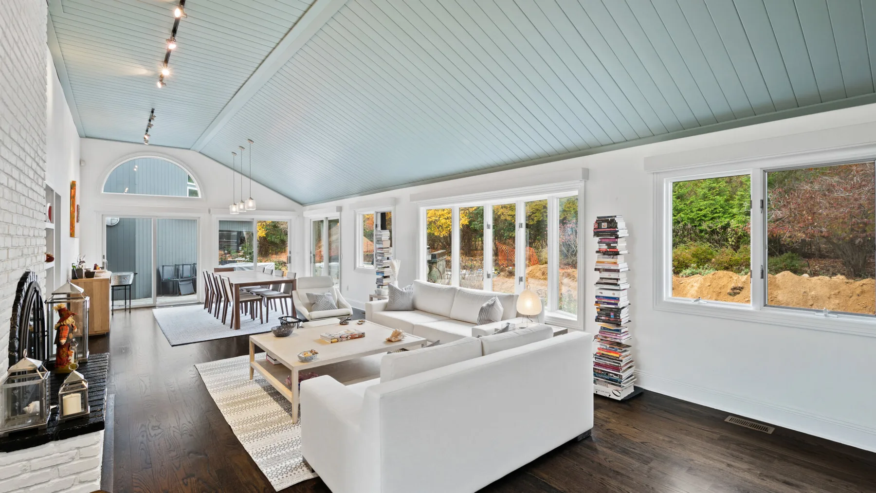 A bright living room with seating, large windows, and a dining area.