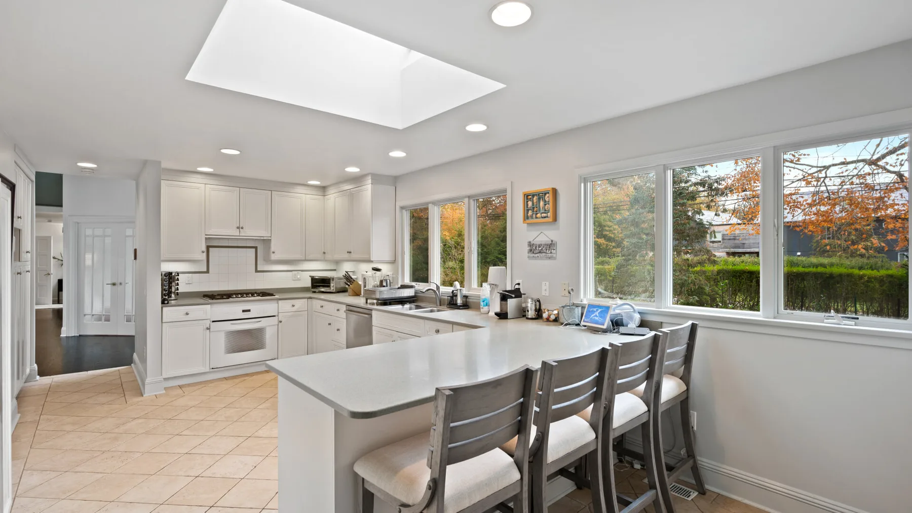 A bright kitchen with white cabinets, a central island, and wide windows.