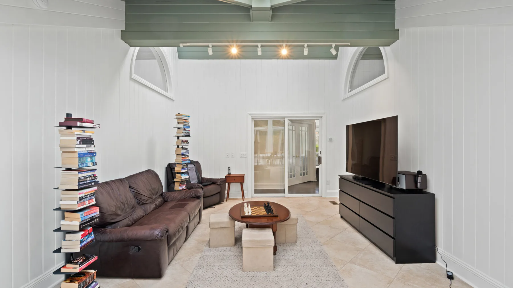 A bright living room with seating, a coffee table, and a television.