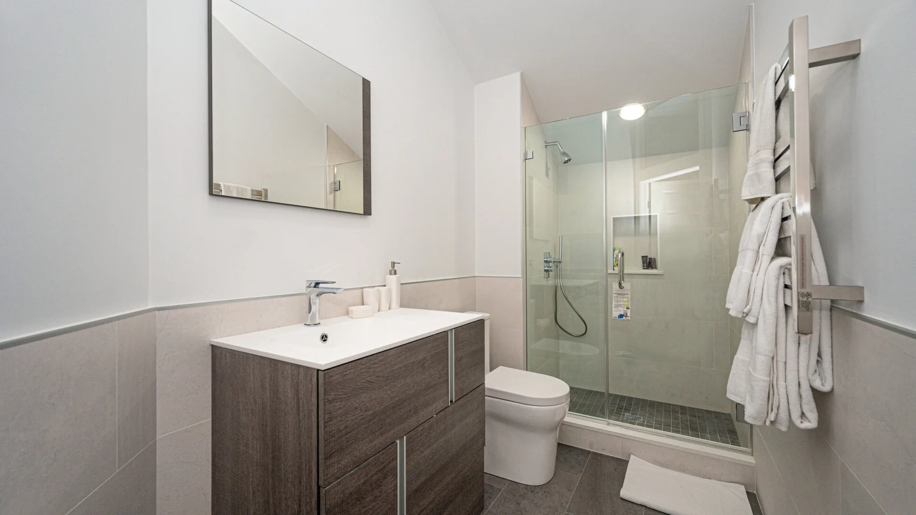 A bathroom with a vanity, toilet, and glass-enclosed shower.