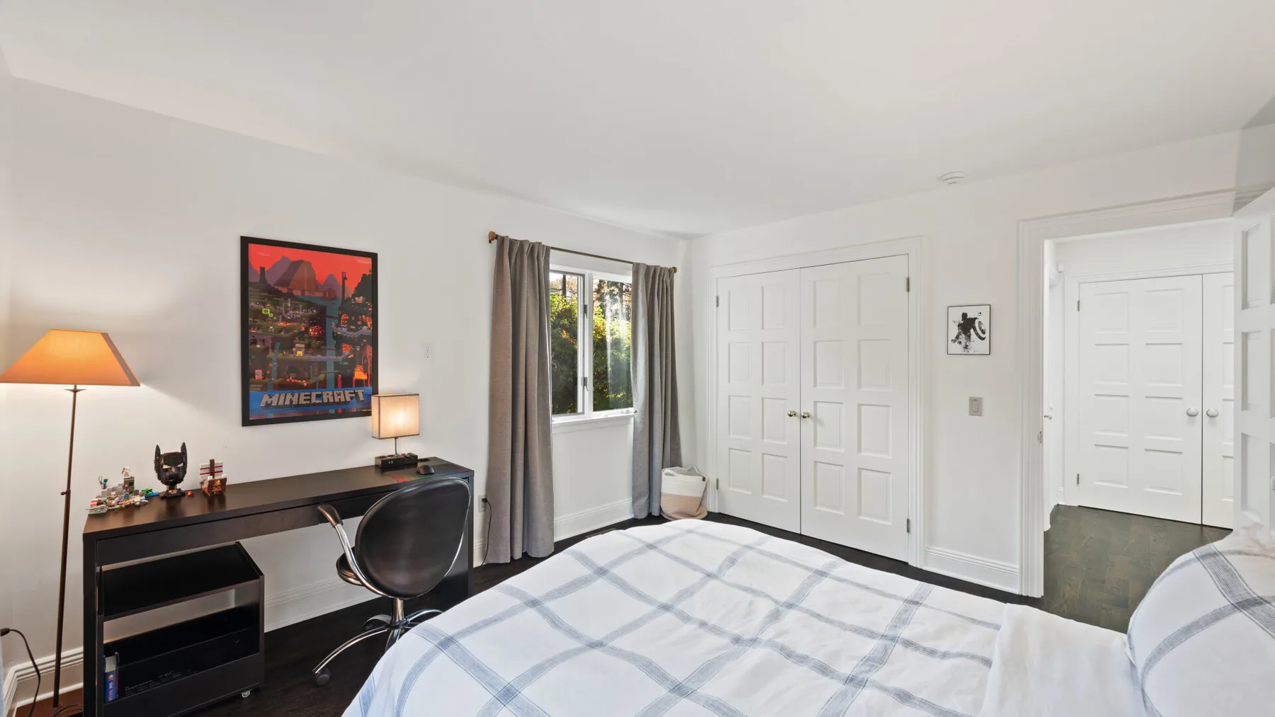 A bedroom with a bed, desk, and curtained window.