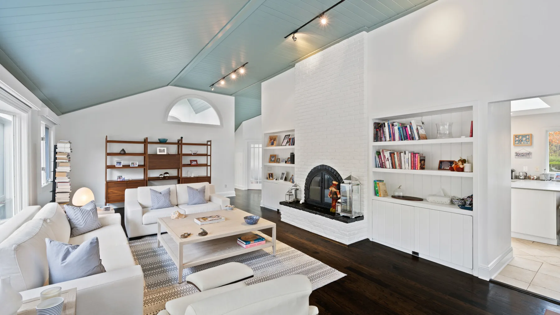 A bright living room with seating, a fireplace, and built-in bookshelves.
