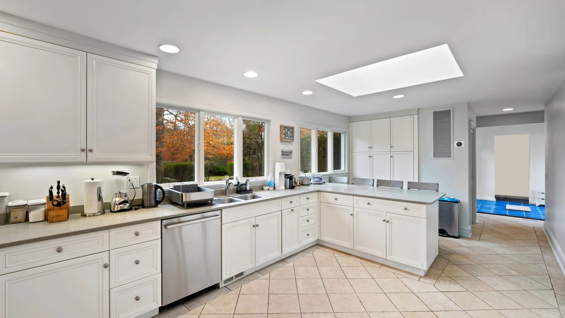 A bright white kitchen with long counters and large windows.