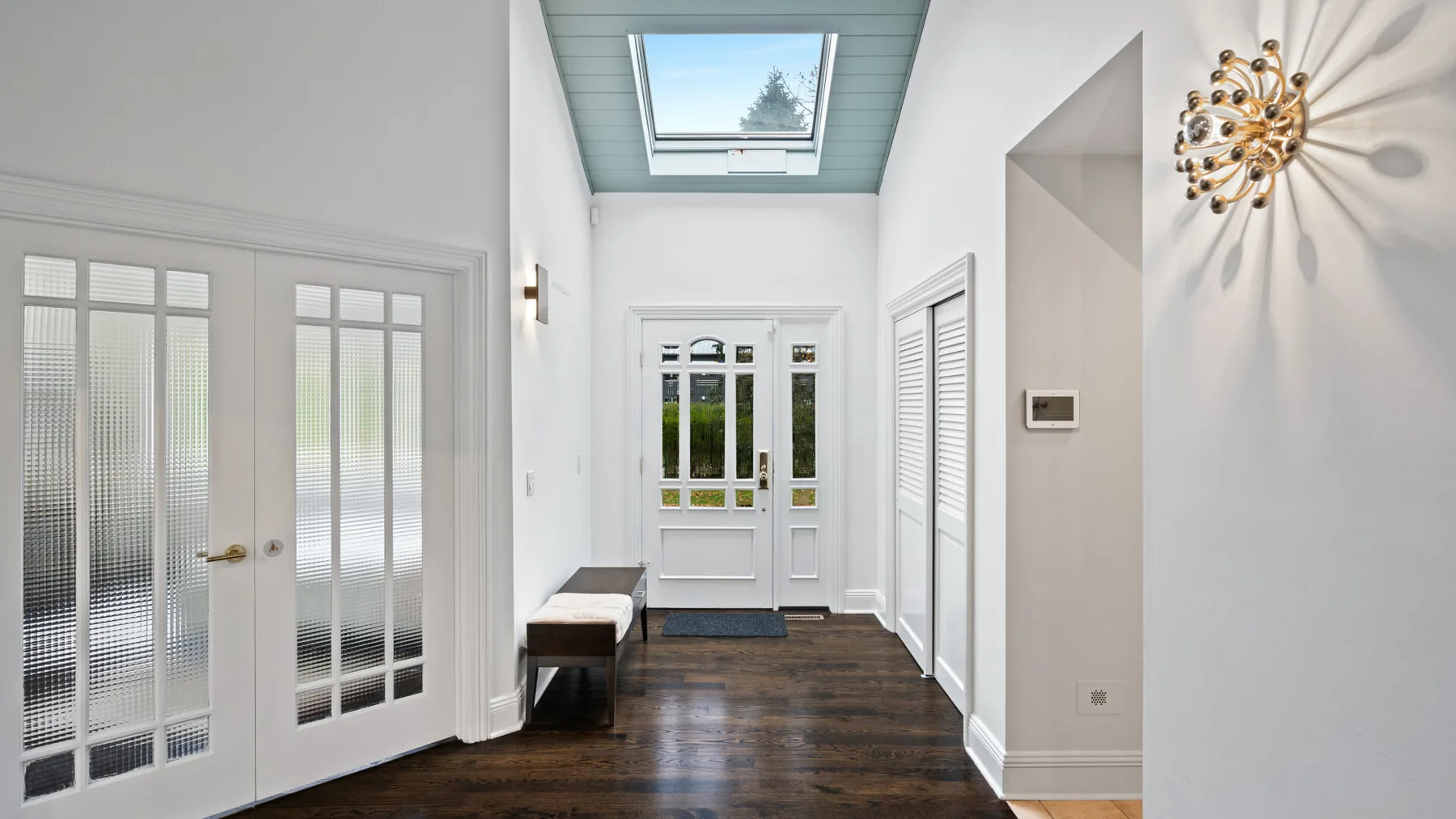 A bright entry hall with glass-paneled doors and a skylight.