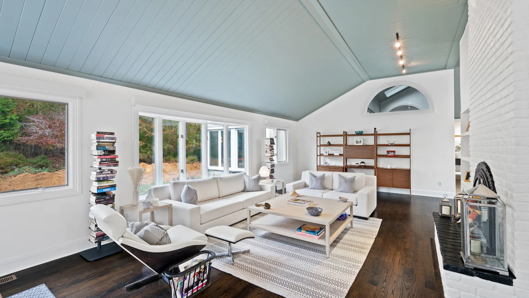 A bright living room with seating arranged around a coffee table beneath a vaulted ceiling.