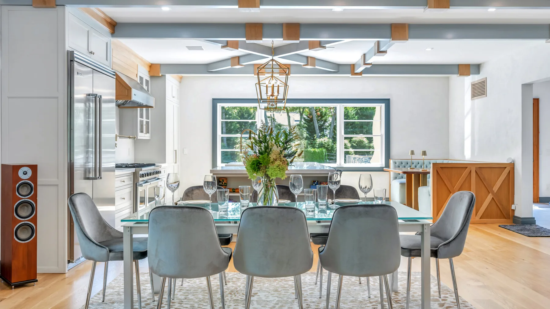 A modern dining area with a glass table and chairs beside a bright kitchen.