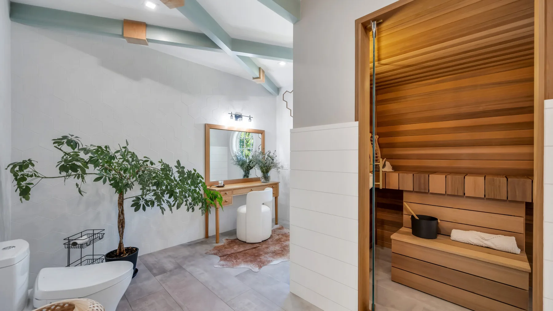 A bathroom with a wooden sauna and a sink area beside a potted plant.