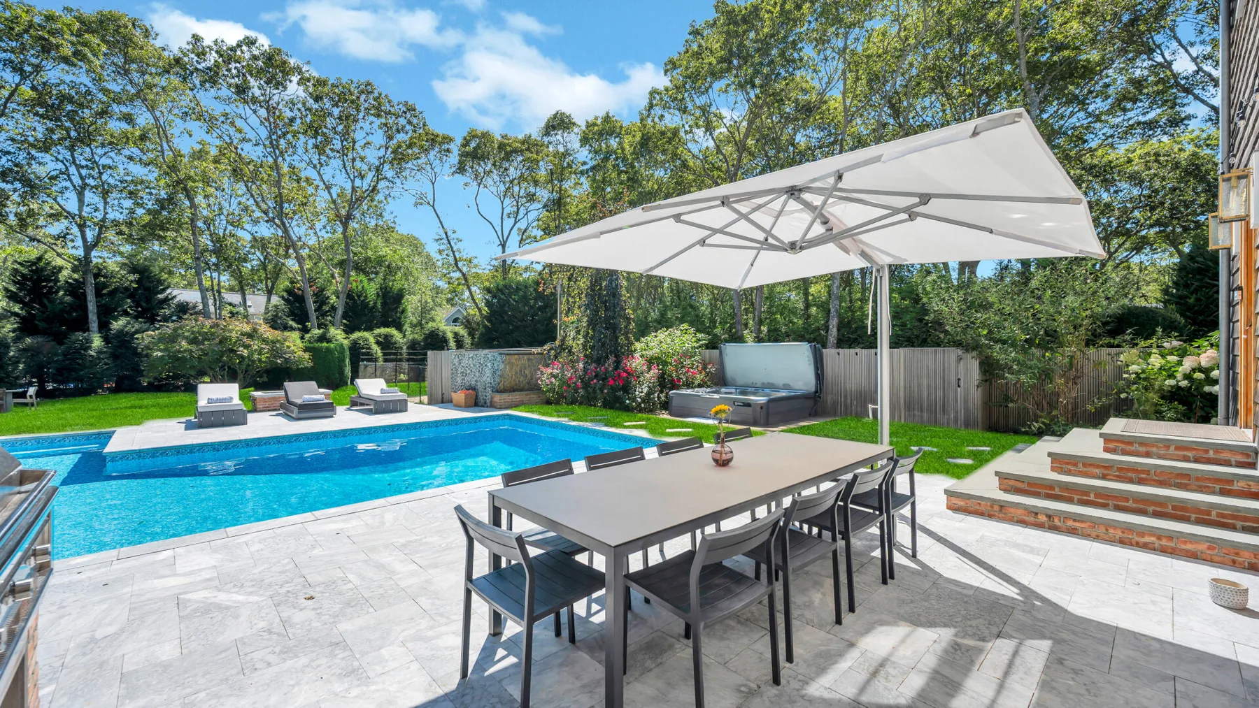 An outdoor patio with a dining table beside a swimming pool.