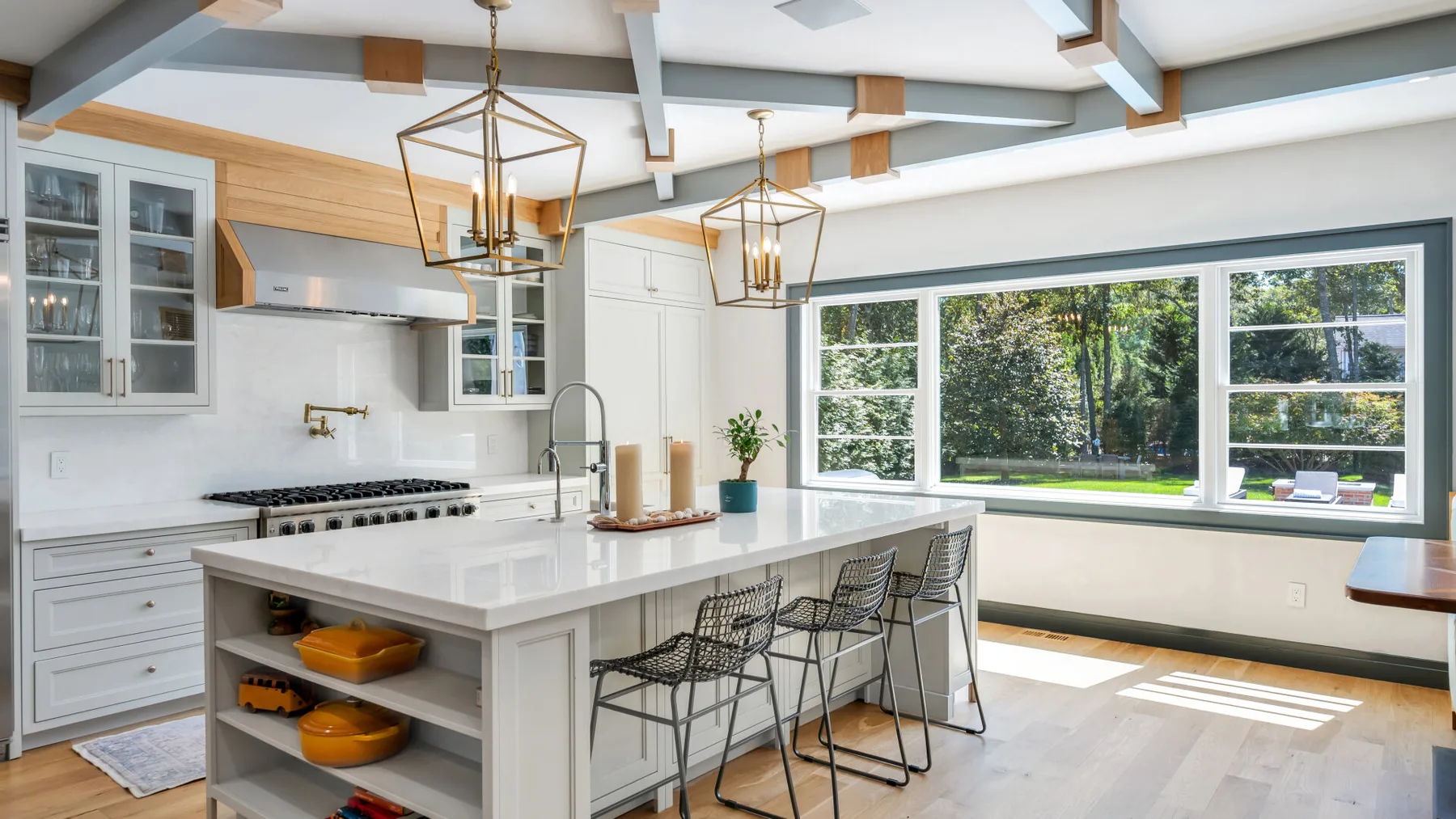 A bright kitchen with a large island and windows overlooking greenery.
