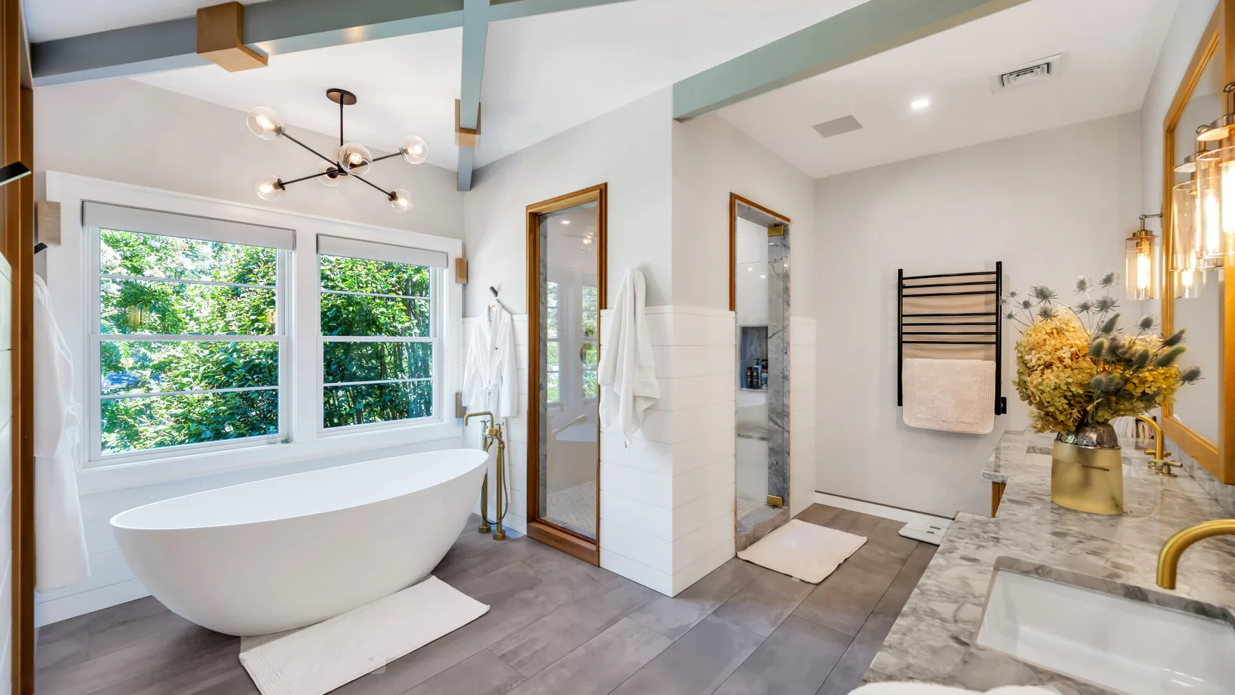 A bright bathroom features a freestanding tub beside large windows.
