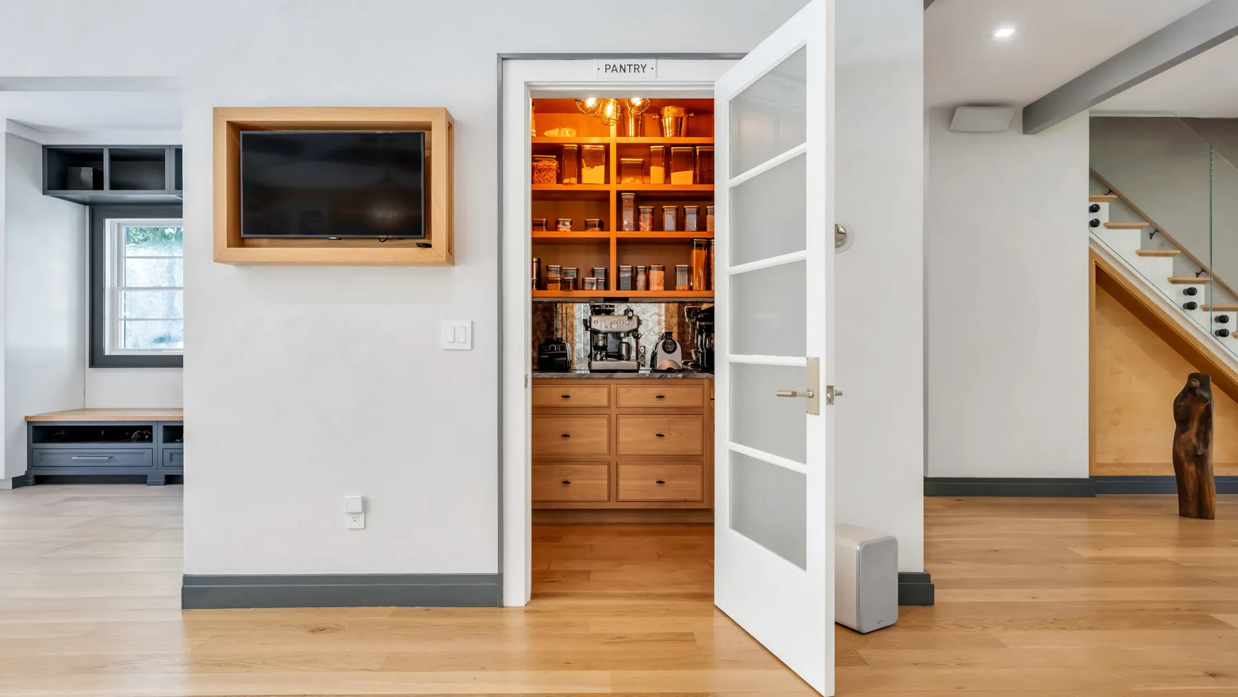 A bright interior with an open doorway, built-in shelving, and a television.