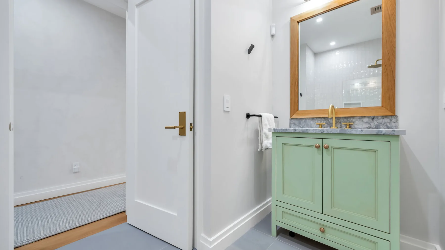 A bathroom vanity with a mirror stands beside an open doorway.