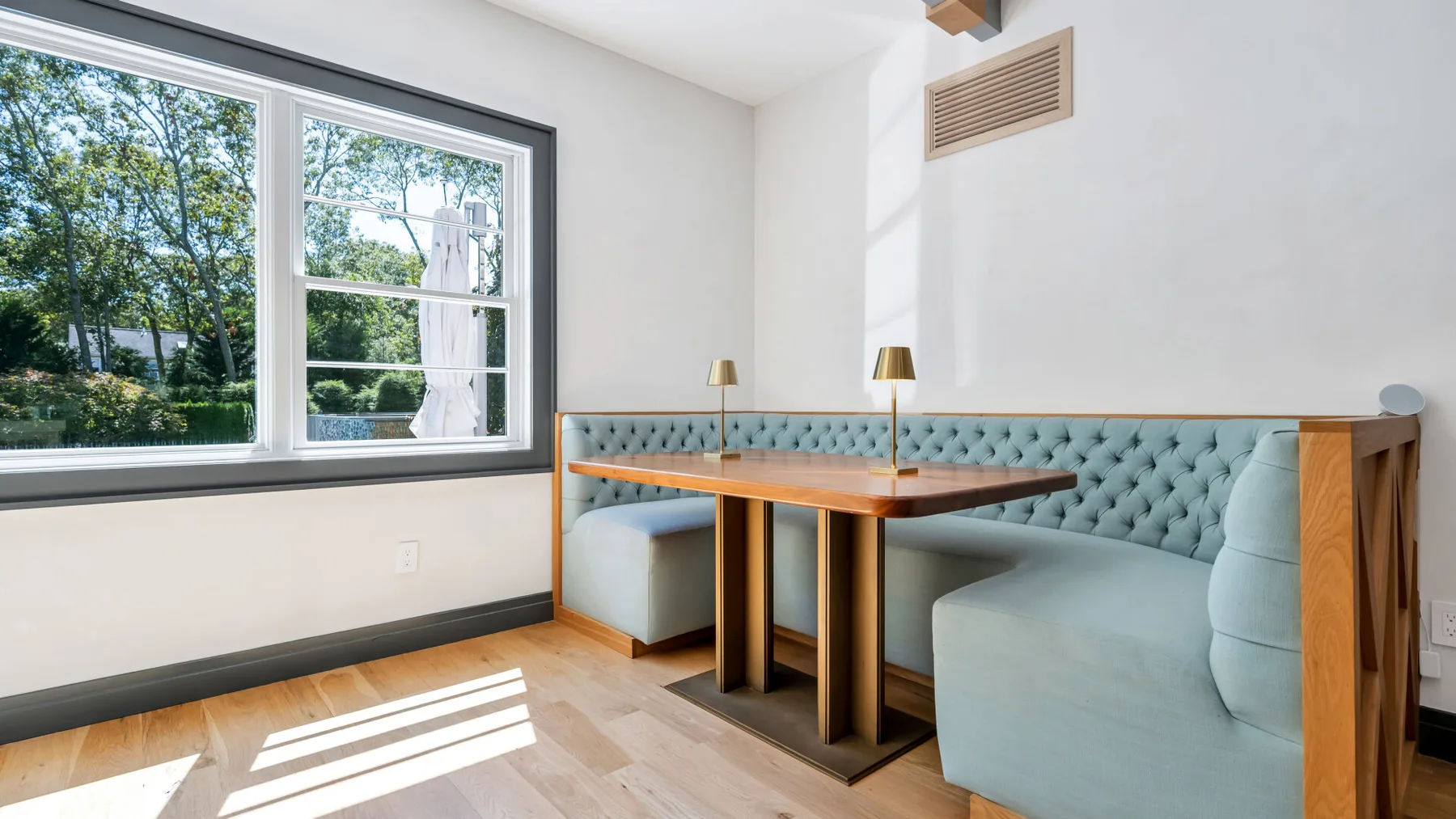 A bright dining nook with a built-in booth beside large windows.