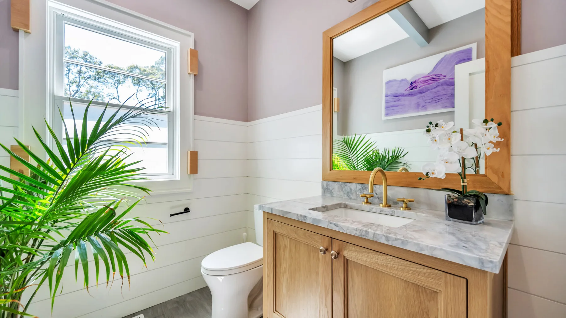 A bathroom with a wood vanity, sink, and window.