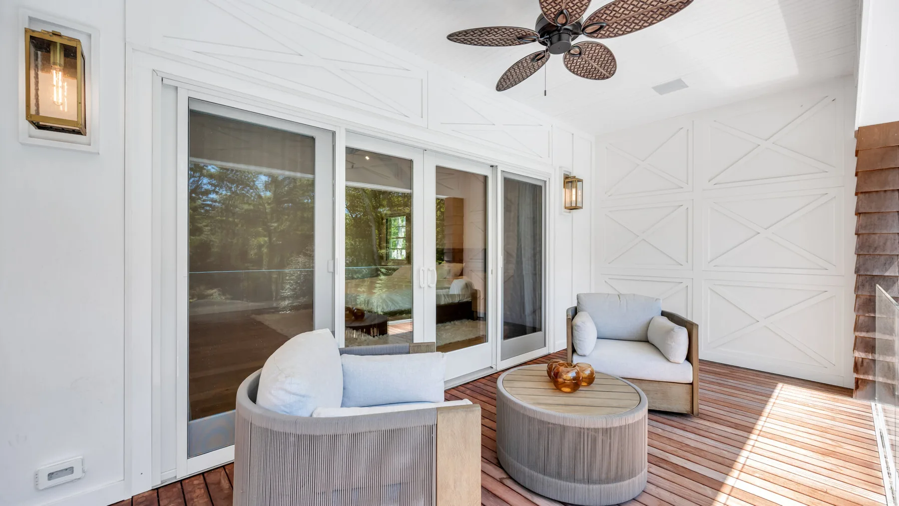 A bright living room with sliding glass doors and seating beside a striped rug.