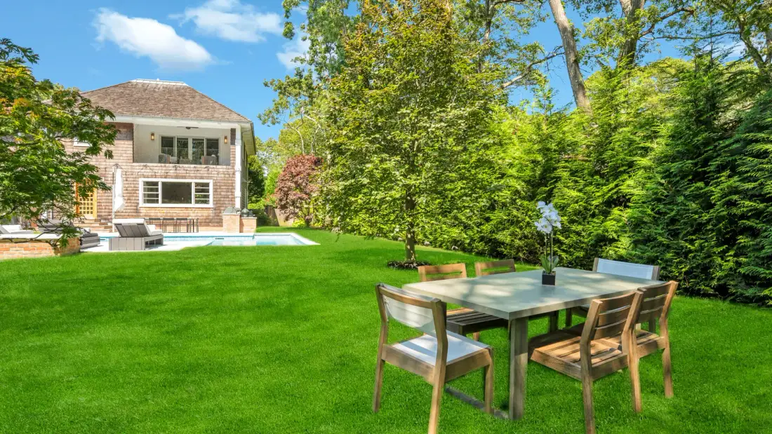 A garden dining area with a table and seating beside a green lawn.