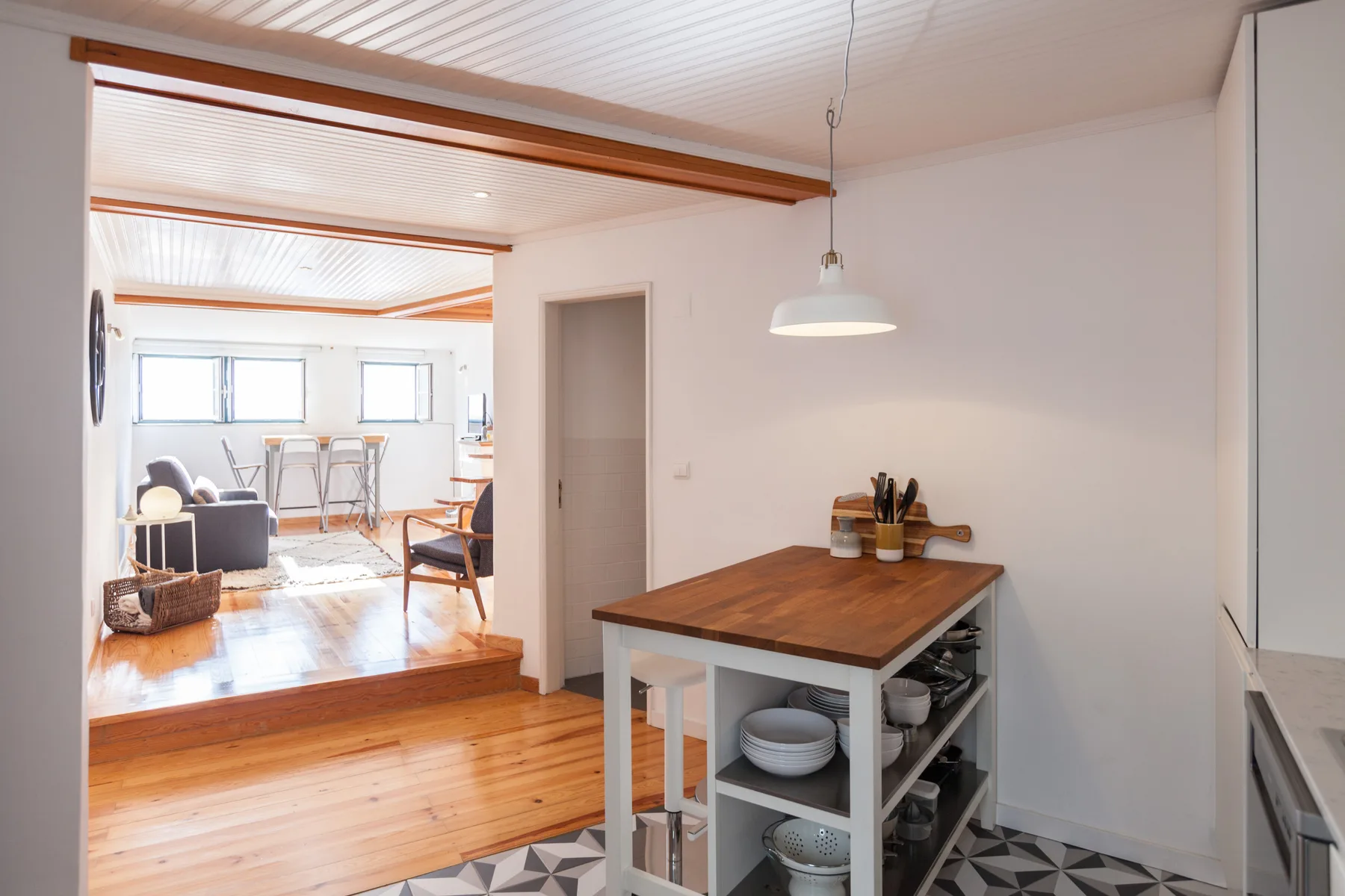 A bright kitchen and dining area with a wooden island and open shelves.