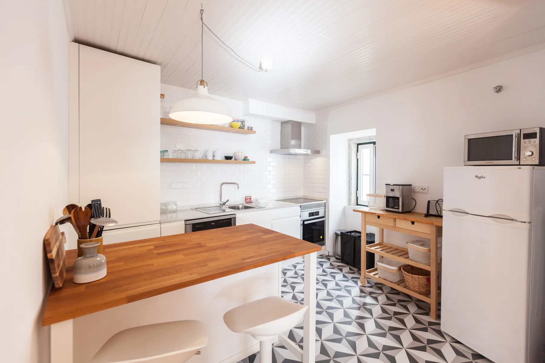 A bright kitchen with a wooden counter and patterned floor.