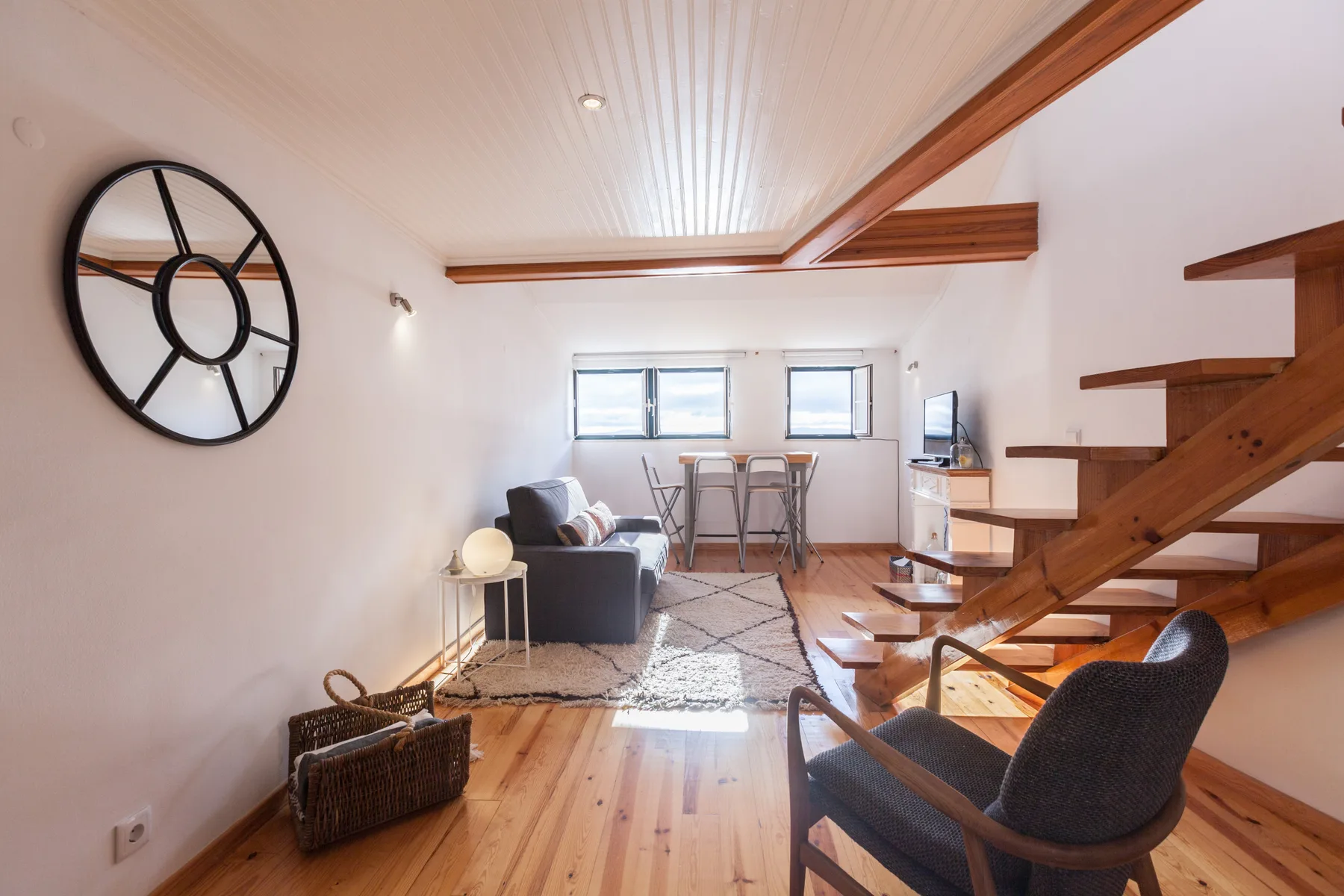 Living room with seating, a dining area, and an open wooden staircase.