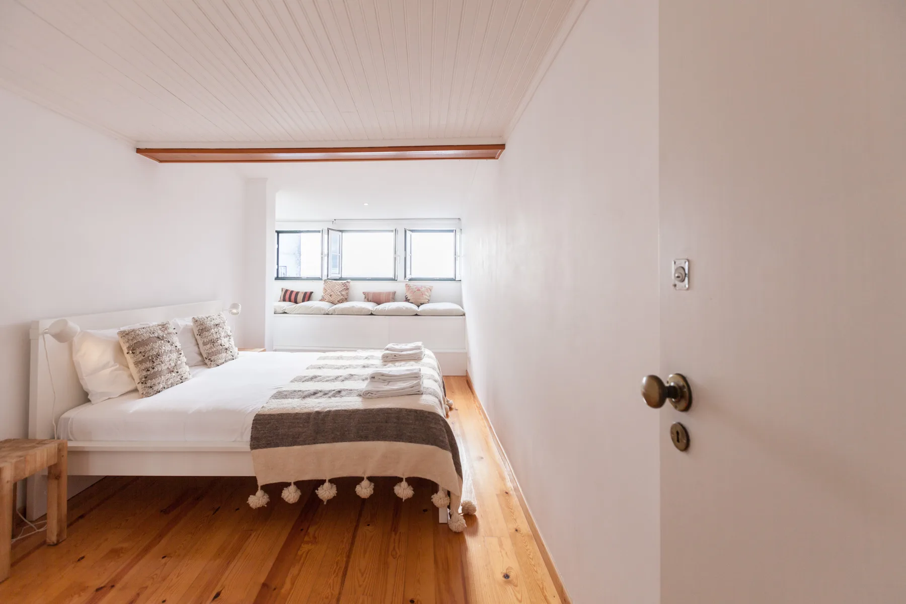 Un dormitorio luminoso con una cama y un banco junto a la ventana.