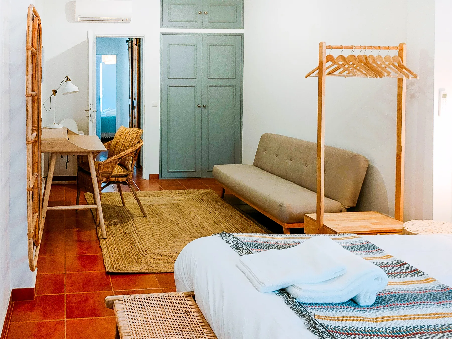A bedroom with a bed, a seating area, and a small desk.
