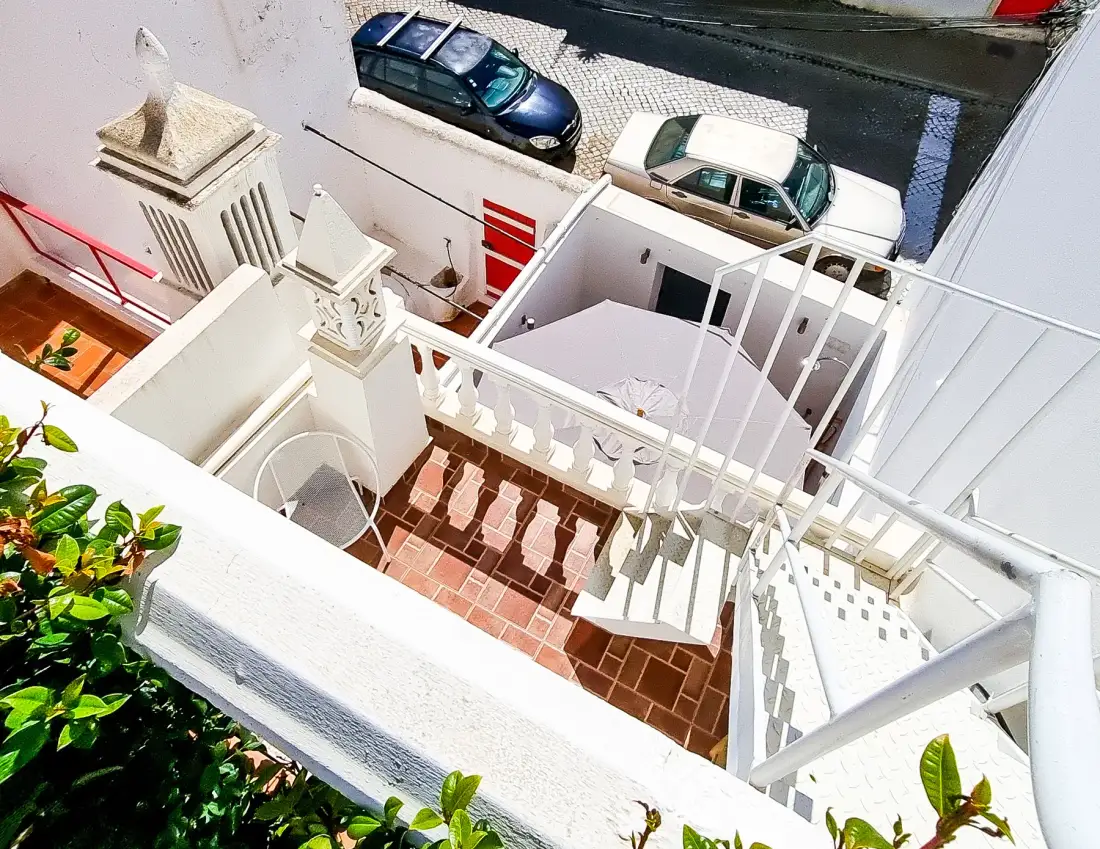 A rooftop terrace with tiled flooring and white railings overlooks the street.