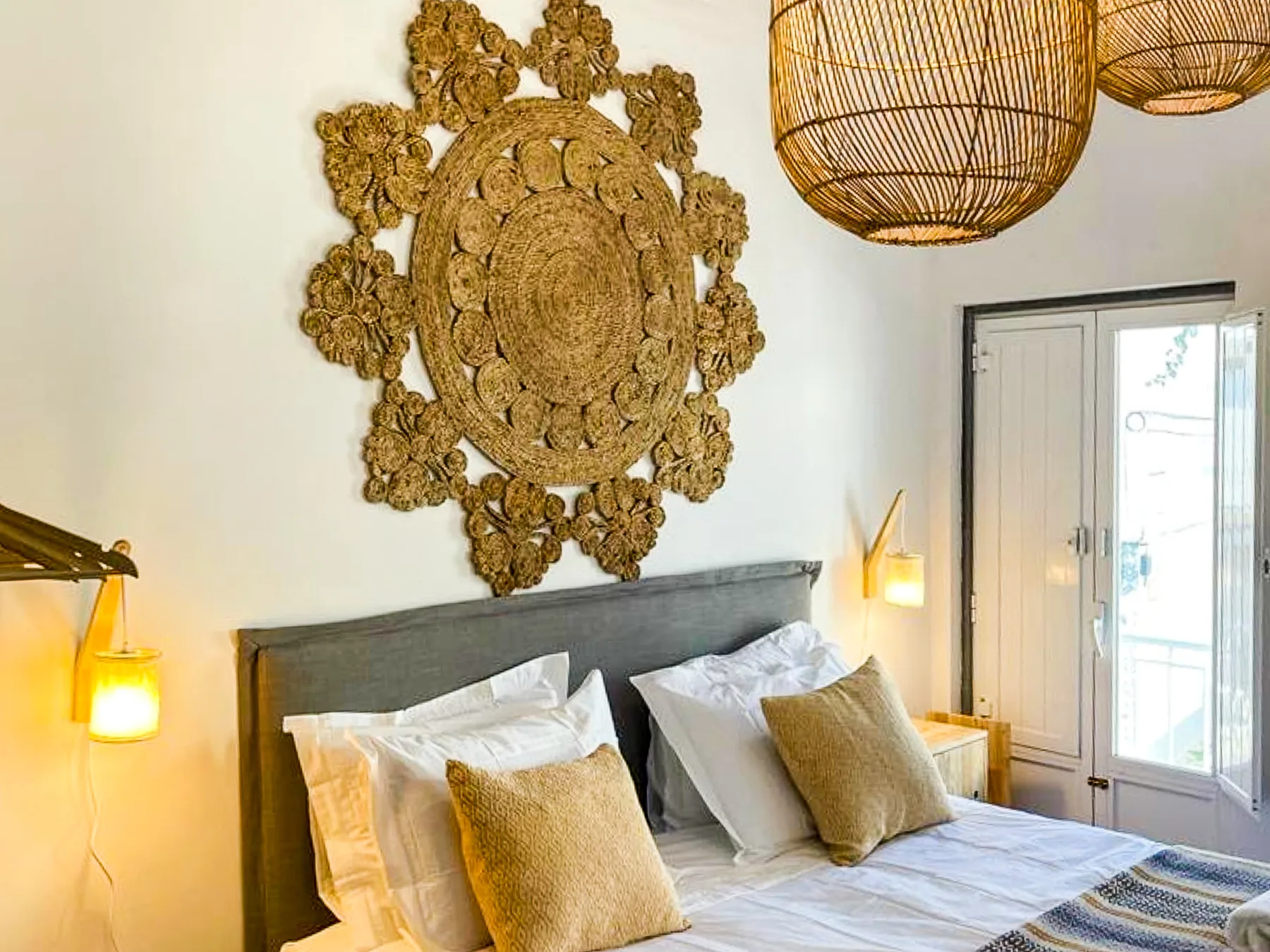 A bedroom with a bed beneath an ornate woven wall decoration.