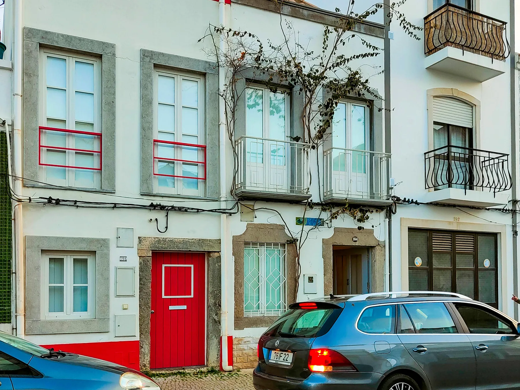A row of townhouses with balconies and parked cars along the street.