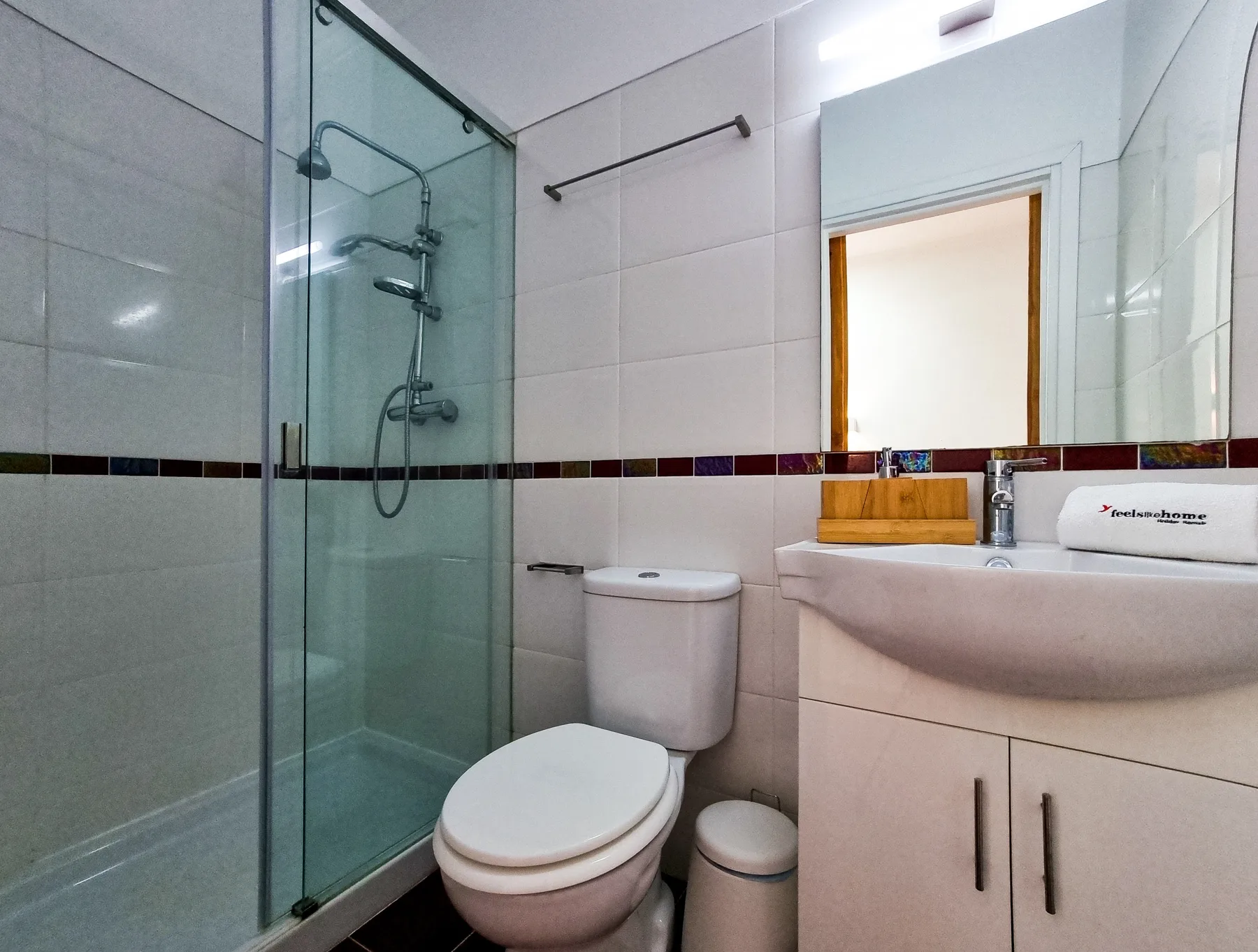 A bathroom with a glass shower, toilet, and sink.