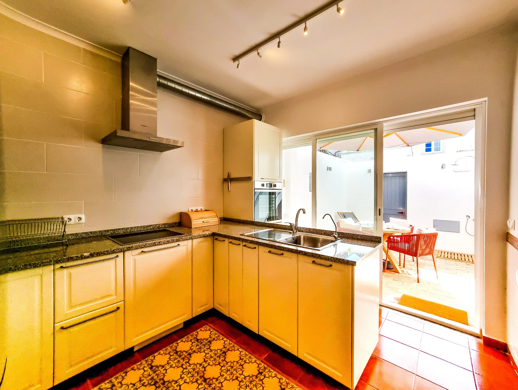 A bright kitchen with yellow cabinetry opens onto an outdoor patio.