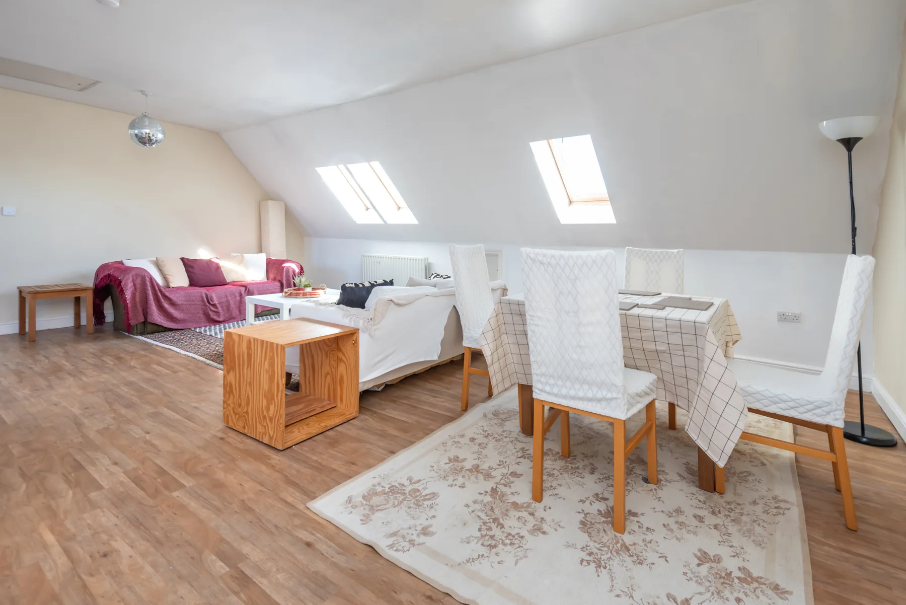 Una luminosa habitación abuhardillada combina una zona de comedor con asientos y un sofá.