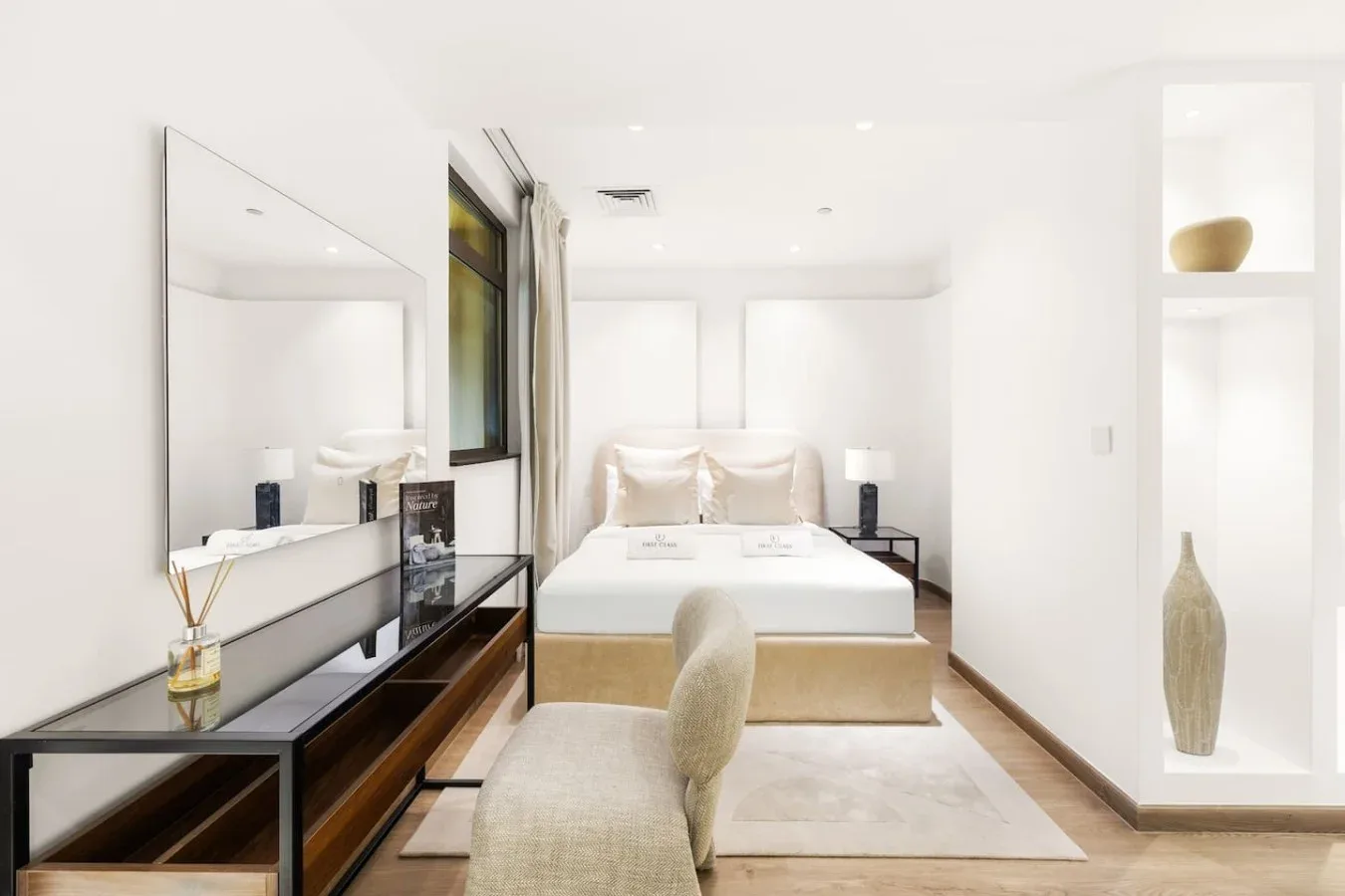 Bright bedroom with a bed, bedside tables, and a cushioned seat.